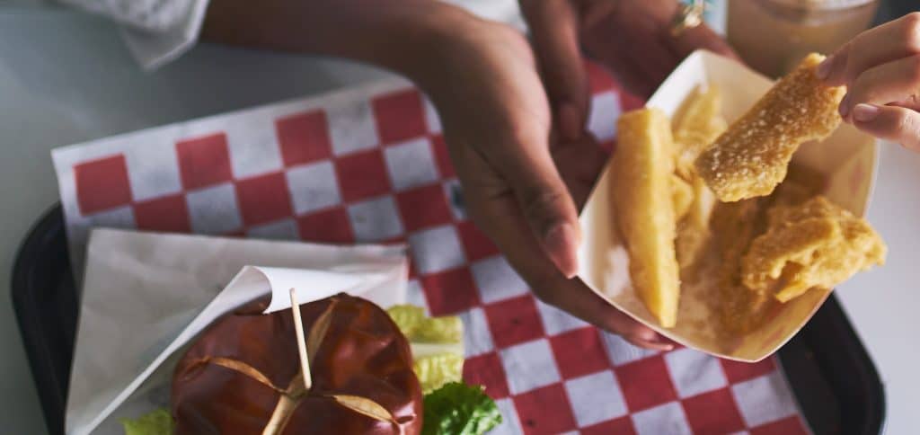 two woman sharing healthy vegan yucca root fries and eating meal together at vegan restaurant